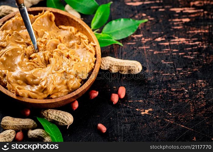 Peanut butter on a plate with a spoon. Against a dark background. High quality photo. Peanut butter on a plate with a spoon.