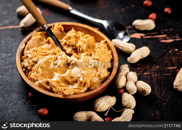 Peanut butter on a plate with a spoon. On a rustic dark background. High quality photo. Peanut butter on a plate with a spoon.