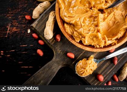 Peanut butter on a plate with a spoon. On a rustic dark background. High quality photo. Peanut butter on a plate with a spoon.