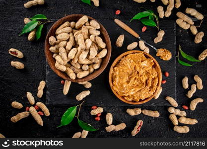 Peanut butter on a stone board with peanuts in the shell. On a black background. High quality photo. Peanut butter on a stone board with peanuts in the shell.