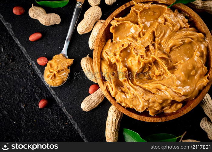 Peanut butter on a stone board with peanuts in the shell. On a black background. High quality photo. Peanut butter on a stone board with peanuts in the shell.