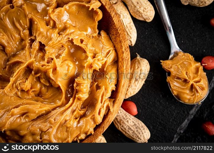Peanut butter on a stone board with peanuts in the shell. On a black background. High quality photo. Peanut butter on a stone board with peanuts in the shell.