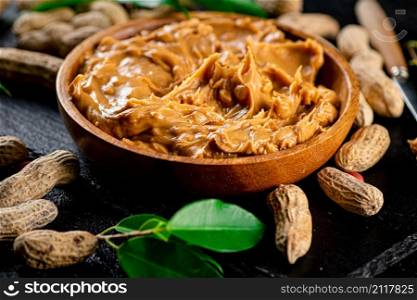 Peanut butter on a stone board with peanuts in the shell. On a black background. High quality photo. Peanut butter on a stone board with peanuts in the shell.