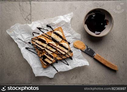 Peanut butter toast with banana slices and chocolate. Healthy breakfast or snack on grey concrete background., top view. Peanut butter toast