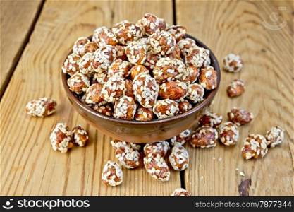 Peanut sweet caramel with sesame seeds in a bowl on a wooden boards background