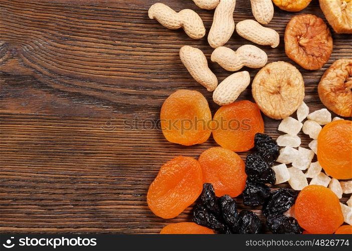 Peanuts and dried fruits on a wooden background