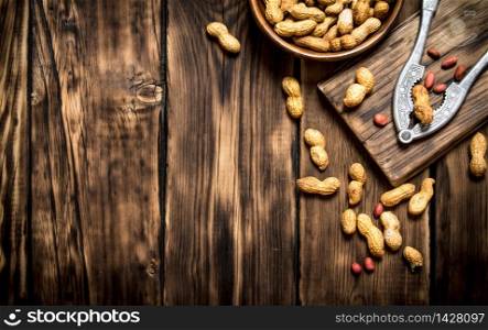 Peanuts in a bowl with a Nutcracker on the Board. On wooden background.. Peanuts in a bowl