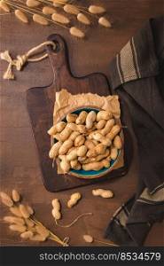 Peanuts in a ceramic bowl on a rustic kitchen countertop.