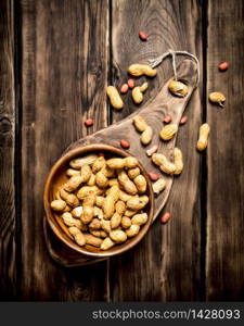 Peanuts in a wooden bowl . On wooden background.. Peanuts in a wooden bowl .