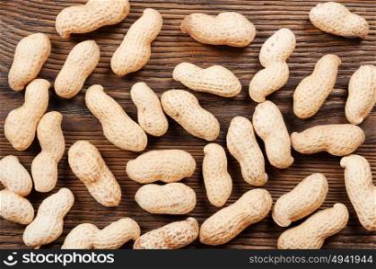 Peanuts in shell scattered on a wooden table. Background with nuts.