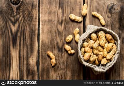 Peanuts in the old bag. On wooden background.. Peanuts in the old bag.