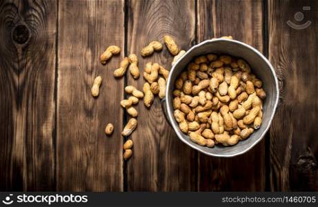 Peanuts in the old pot. On wooden background.. Peanuts in the old pot.