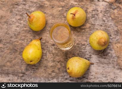 pear and a glass of juice on a wooden table, studio picture
