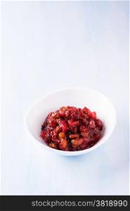 Pear cranberry relish in a white bowl over light blue background with copy space