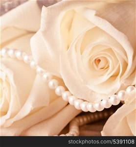Pearl beads and cream rose on the silk background