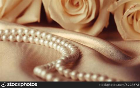 Pearl beads and cream rose on the silk background. Pearl beads and cream rose
