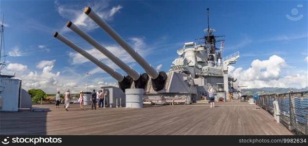 Pearl Harbor, Hawaii, USA - September 24, 2018  Panoramic shot of huge cannons and deck of USS Missouri docked in Pearl Harbor. Deck full of tourists. Blue sky with white clouds as a background.. Pearl Harbor, Hawaii, USA - September 24, 2018  Panoramic shot of huge cannons and deck of USS Missouri docked in Pearl Harbor. Deck full of tourists. Blue sky with white clouds as a background