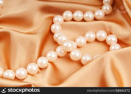 Pearl necklace on the bright satin background