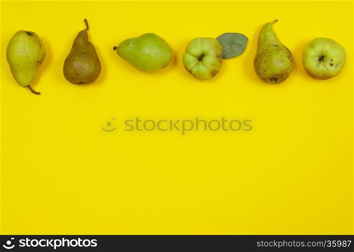 Pears and quince in row on yellow background with copy space