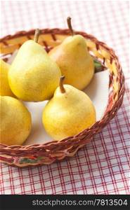 pears in a wooden basket lying on a plaid fabric