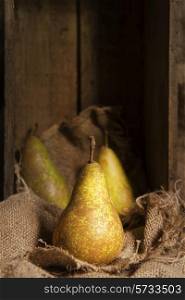Pears in rustic setting with wooden box and hessian sack