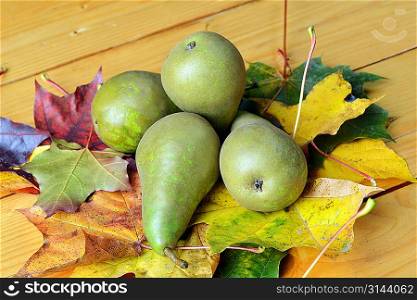 pears with colorful dried autumn leaves on wooden table