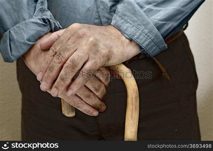 Peasant hands, leaning on a cane placed in front of him