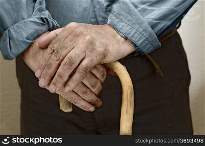 Peasant hands, leaning on a cane placed in front of him