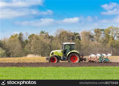 Peasant on tractor plowing sandy soil in spring season