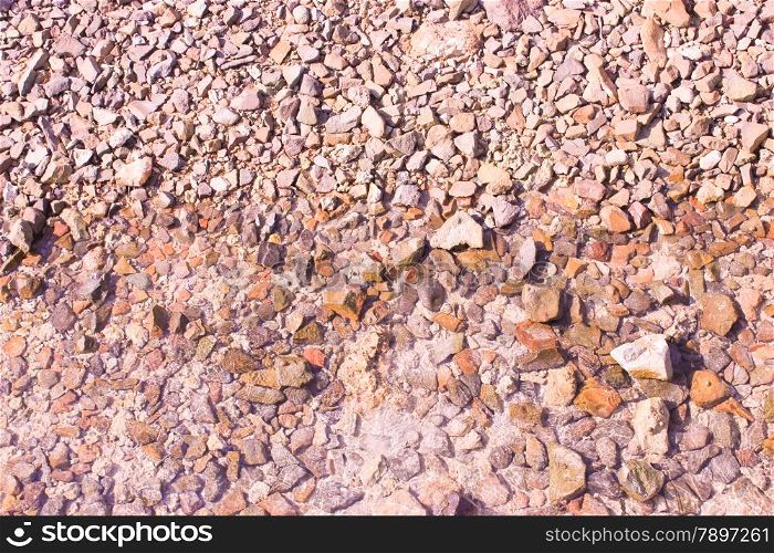 Pebble background at sun light. Stone texture.