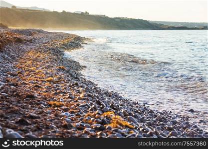 Pebble beach on sea coast at sunset