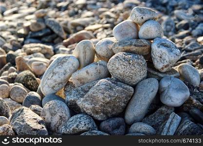 Pebble stones stacked by a heap on the beach in the sun as a texture or background