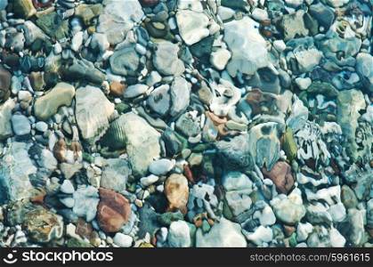Pebbles on sea shore over water background