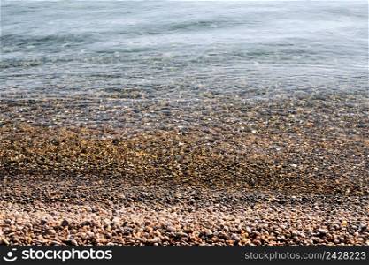 Pebbles on the beach close up on the sea surf background, copy space. Calm clear sea, Black Sea coast
