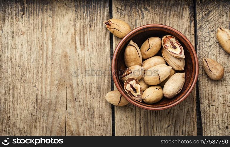 Pecan nuts in bowl on a rustic wooden table. Unshelled pecans nut