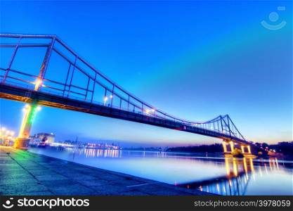 Pedestrian bridge in Kyiv, shoted in dusk illuminated with different colors
