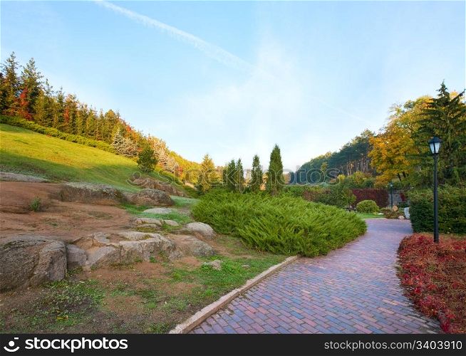 Pedestrian path and fir trees on hill in beautiful autumn city park