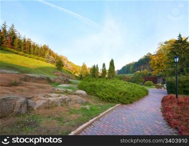 Pedestrian path and fir trees on hill in beautiful autumn city park