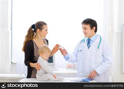 Pediatric doctor giving bottle of vitamins to mother&#xA;