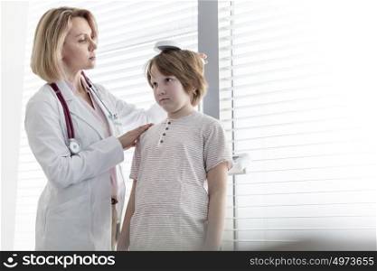 Pediatrician checking height of boy in examination room