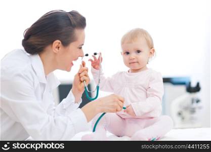 Pediatrician doctor playing with baby on examination
