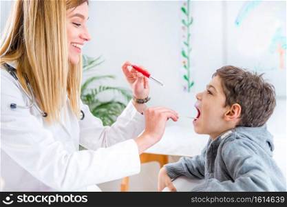 Pediatrician examining boy’s throat with pen torch and tongue depressor
