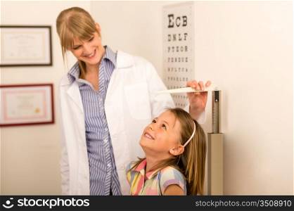 Pediatrician measure height of little girl at medical office