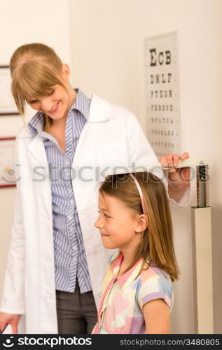 Pediatrician measure height of young girl at medical office