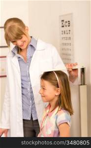 Pediatrician measure height of young girl at medical office