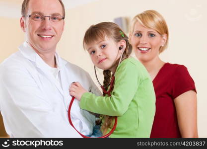 Pediatrician with family - mother and daughter to be seen - in his surgery; he has the child in his arms