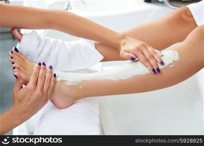 Pedicure aplying nourishing moisturizer mask in legs of woman in nails salon