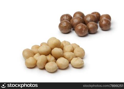 Peeled and unpeeled macadamia nuts on white background