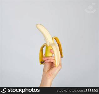 peeled fresh banana in female hand on white background