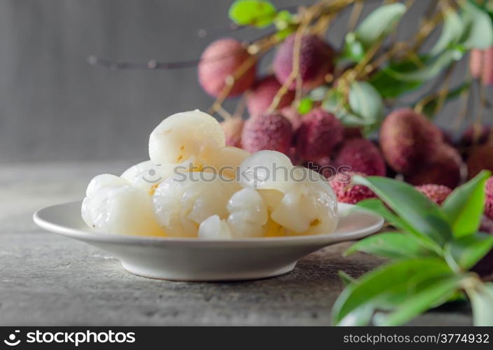 peeled lychee fruit on dish with leaves on a wooden table. Lychee fruit